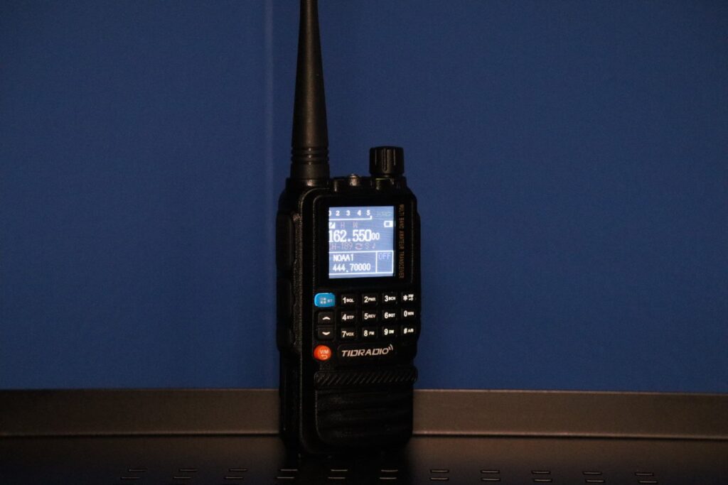 TIDRADIO TD-H3 GMRS radio with display screen illuminated, showing NOAA and UHF frequencies.